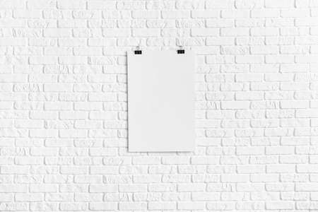 Blank poster hanging on white brick wallの写真素材