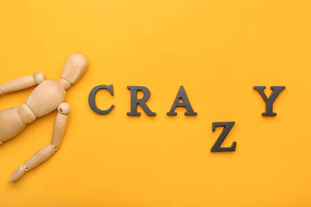 Wooden mannequin with word CRAZY on color backgroundの写真素材