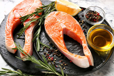 Raw salmon steaks, spices and lemon on tableの写真素材
