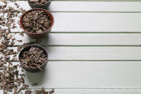 Bowls with dry tea leaves on wooden backgroundの写真素材