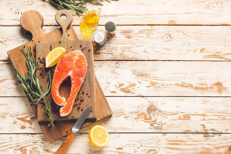 Raw salmon steak and lemon on wooden background