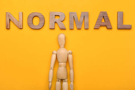Wooden mannequin with word NORMAL on color backgroundの写真素材