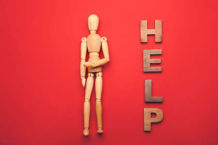 Wooden mannequin with word HELP on color background