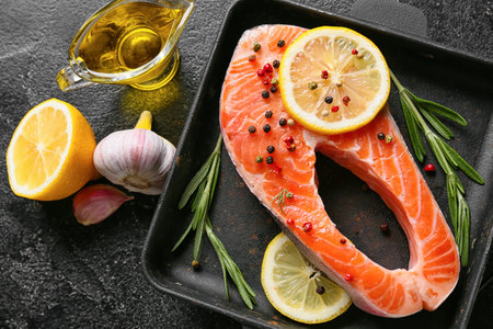 Raw salmon steak and lemon on dark backgroundの写真素材