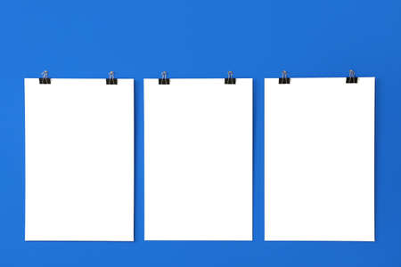Blank posters hanging on color wall