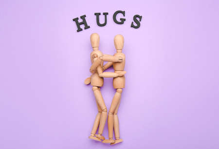 Wooden mannequins with word HUGS on color backgroundの写真素材