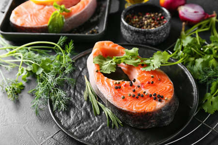 Plate with raw salmon steaks, herbs and spices on dark backgroundの写真素材