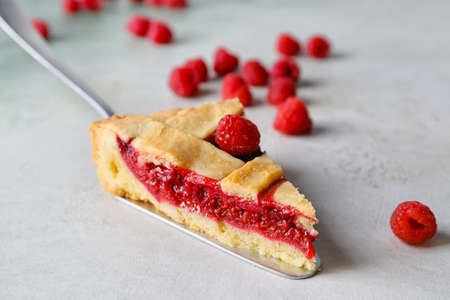 Spatula with piece of tasty raspberry pie on light background, closeup