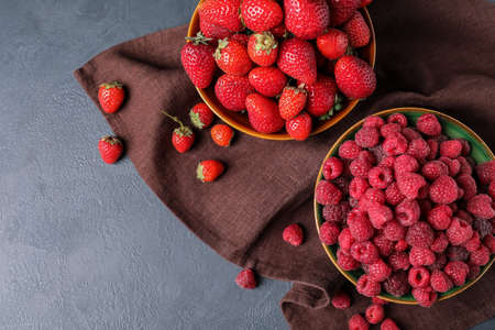 Bowls with ripe strawberry and raspberry on dark backgroundの写真素材