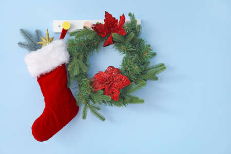 Beautiful Christmas sock with wreath hanging on color wall