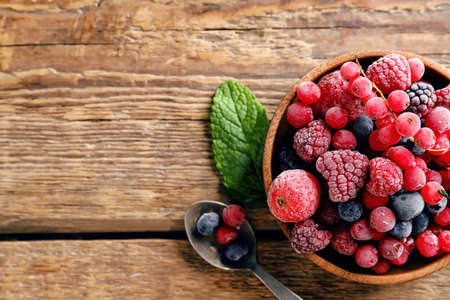 Bowl with tasty frozen berries on wooden backgroundの写真素材