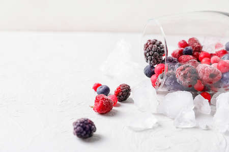 Overturned glass with frozen berries on tableの写真素材
