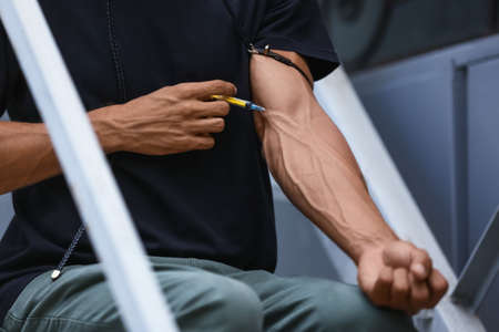 Male junkie making injection outdoors