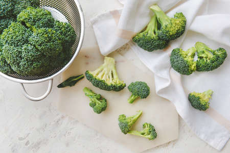 Colander with fresh broccoli cabbage on light backgroundの写真素材