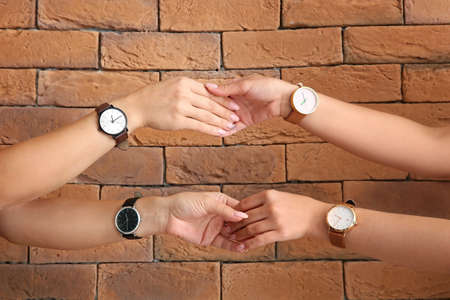 Women with wrist watches shaking hands near brick wallの写真素材
