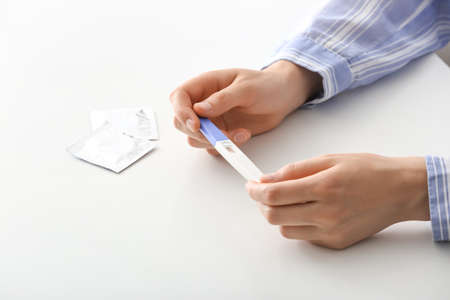 Woman holding pregnancy test at table