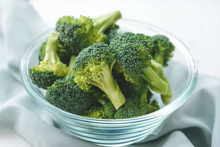 Bowl with fresh broccoli cabbage on light background