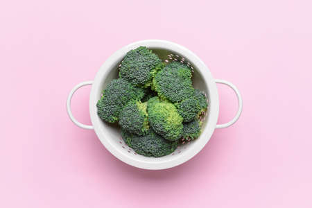 Colander with fresh broccoli cabbage on color backgroundの写真素材