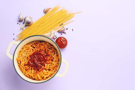 Cooking pot with pasta and ingredients on color backgroundの写真素材