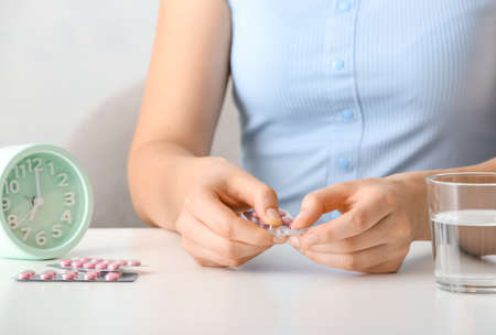 Woman taking birth control pills at tableの写真素材