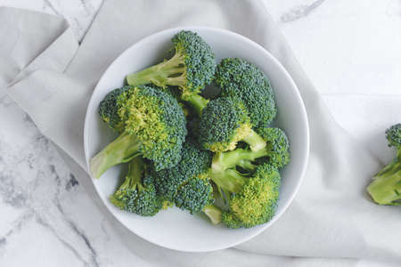 Plate with fresh broccoli cabbage on light backgroundの写真素材
