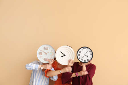 Women with clocks and wrist watches on color backgroundの写真素材