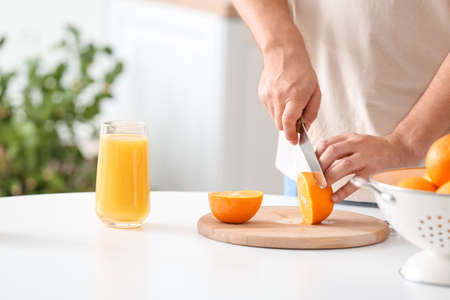 Man cutting orange in kitchen, closeupの写真素材