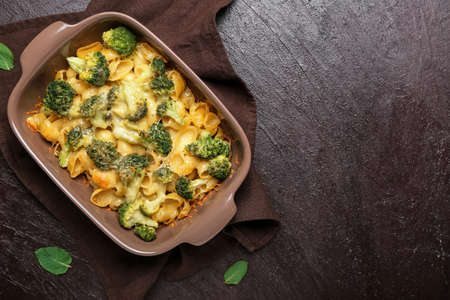 Tasty pasta with broccoli and cheese in baking dish on dark backgroundの写真素材