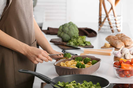 Woman cooking tasty pasta in kitchenの写真素材