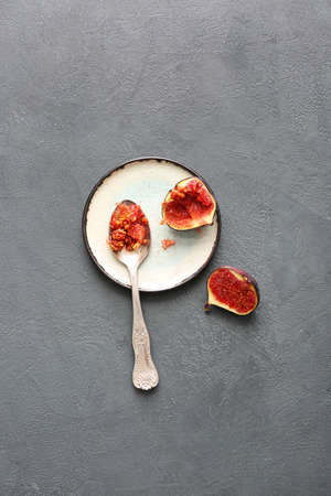 Spoon and cut fig on dark background