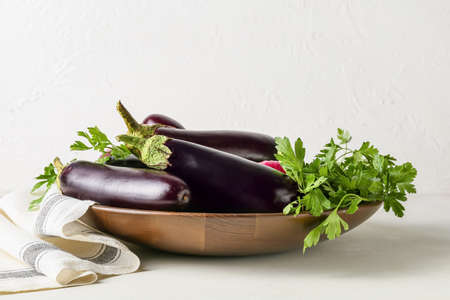 Plate with fresh eggplants on light backgroundの写真素材