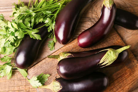 Board with fresh eggplants on wooden backgroundの写真素材
