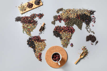 World map made of different sorts of tea and cup with dry hibiscus on light backgroundの写真素材