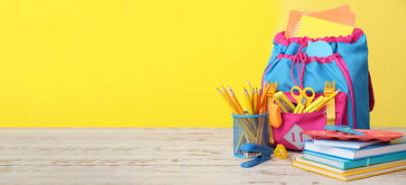 School backpack and stationery on color background with space for text