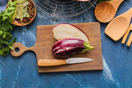 Board with fresh eggplant on color background