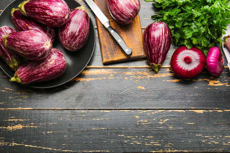 Composition with fresh eggplants on dark wooden background