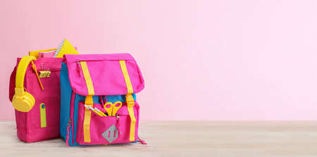 School backpacks on table against color background with space for textの写真素材