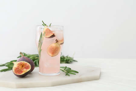 Board with glass of tasty fig lemonade on light backgroundの写真素材
