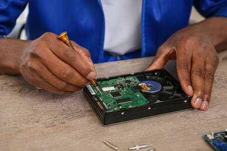 African-American technician repairing computer in service center, closeup