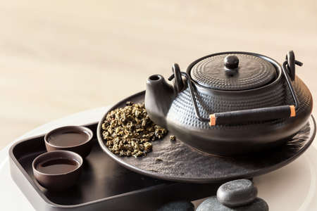 Modern teapot, cups and dry green tea on tableの写真素材
