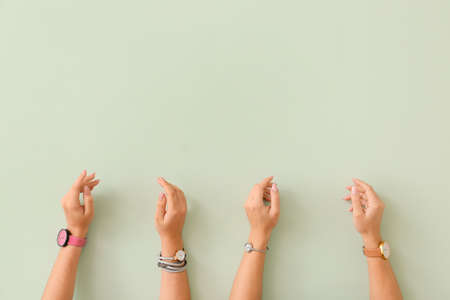 Female hands with watches on color background