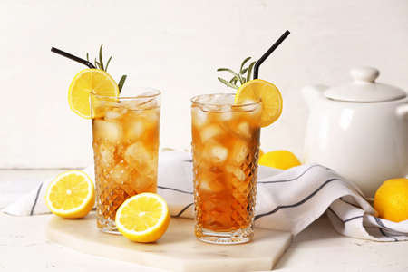 Glasses of cold black tea with lemon on light backgroundの写真素材