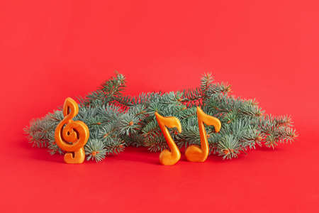 Christmas tree branches with music notes on color background