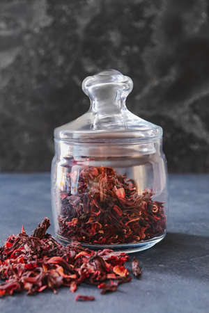 Glass jar with dry hibiscus tea on table