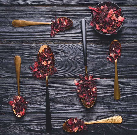 Spoons and bowl with dry hibiscus tea on tableの写真素材