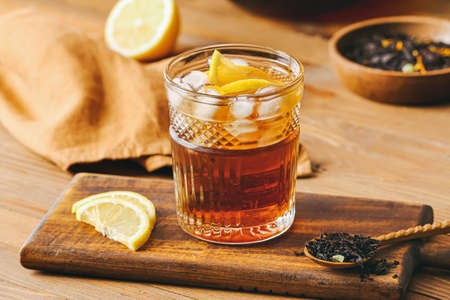 Glass of cold black tea with lemon on wooden backgroundの写真素材