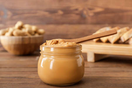 Jar with tasty peanut butter on tableの写真素材