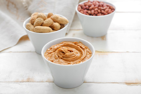 Bowls with tasty peanuts and butter on tableの写真素材
