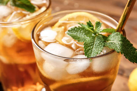 Glass of cold black tea with lemon on wooden background, closeupの写真素材