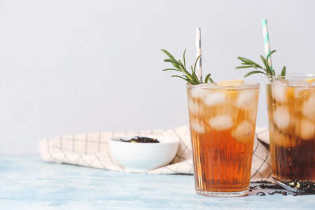 Glasses of cold black tea with lemon on light backgroundの写真素材